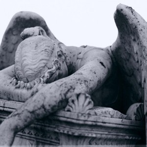 An angel collapsed over a coffin, crying.